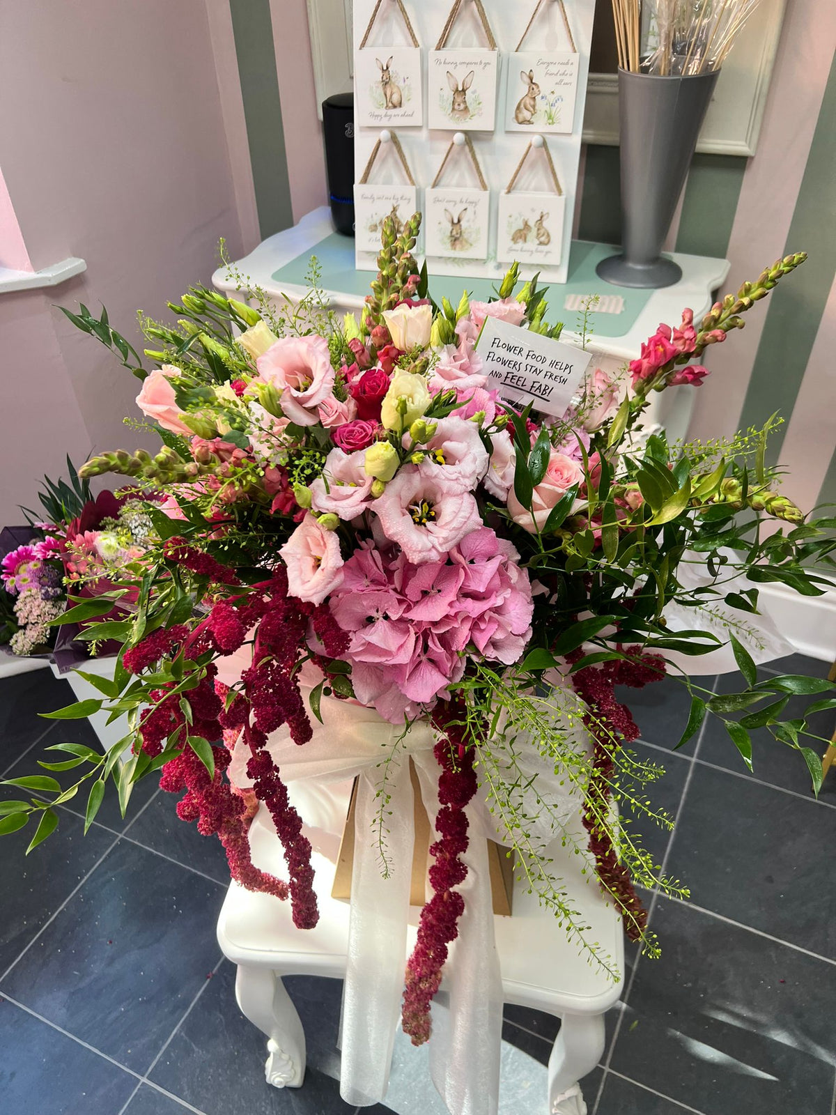 Large pink and burgundy hand-tied arrangement displayed inside The Flower Cottage