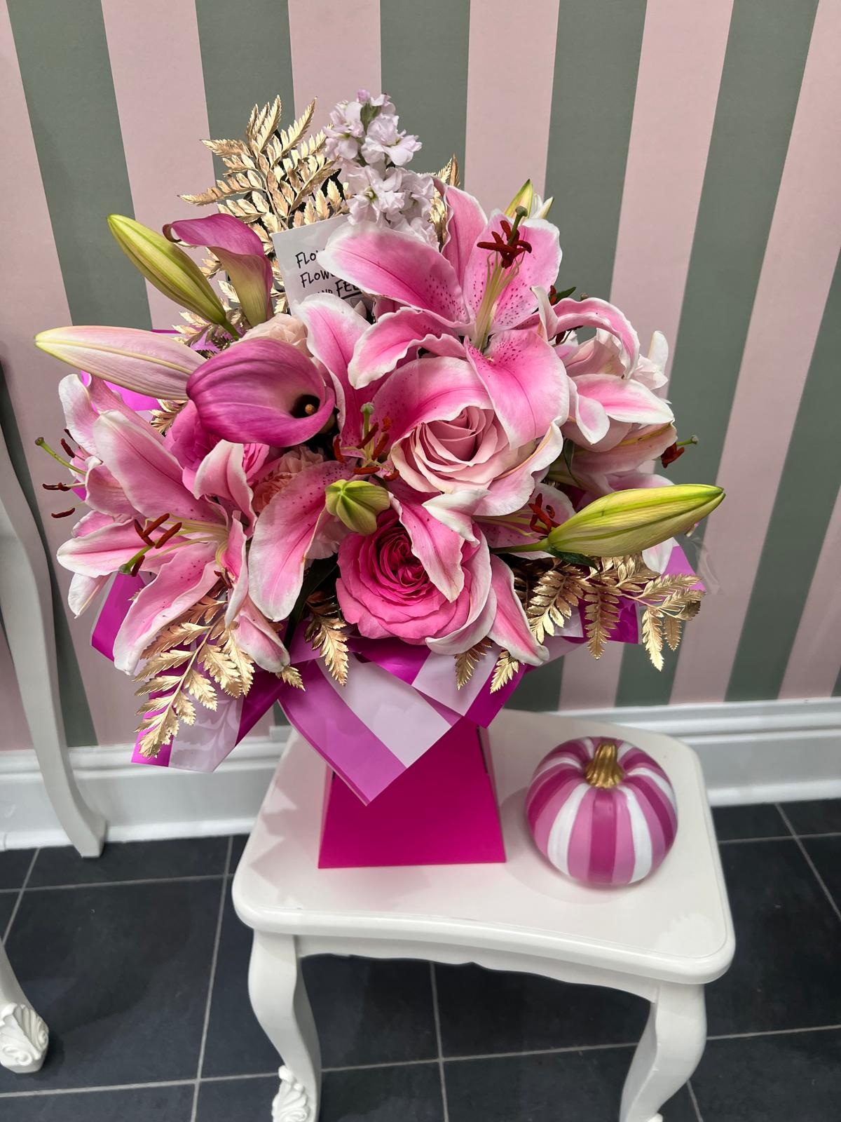 Pink lilies, roses and calla lilies with gold foliage in a pink gift box